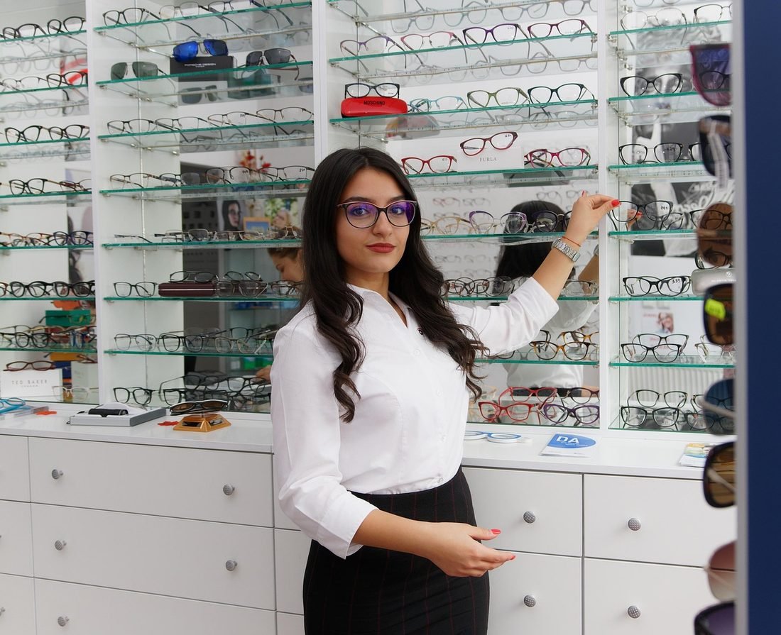 A customer choosing frames from a display wall in a Ben Franklin style optical store.