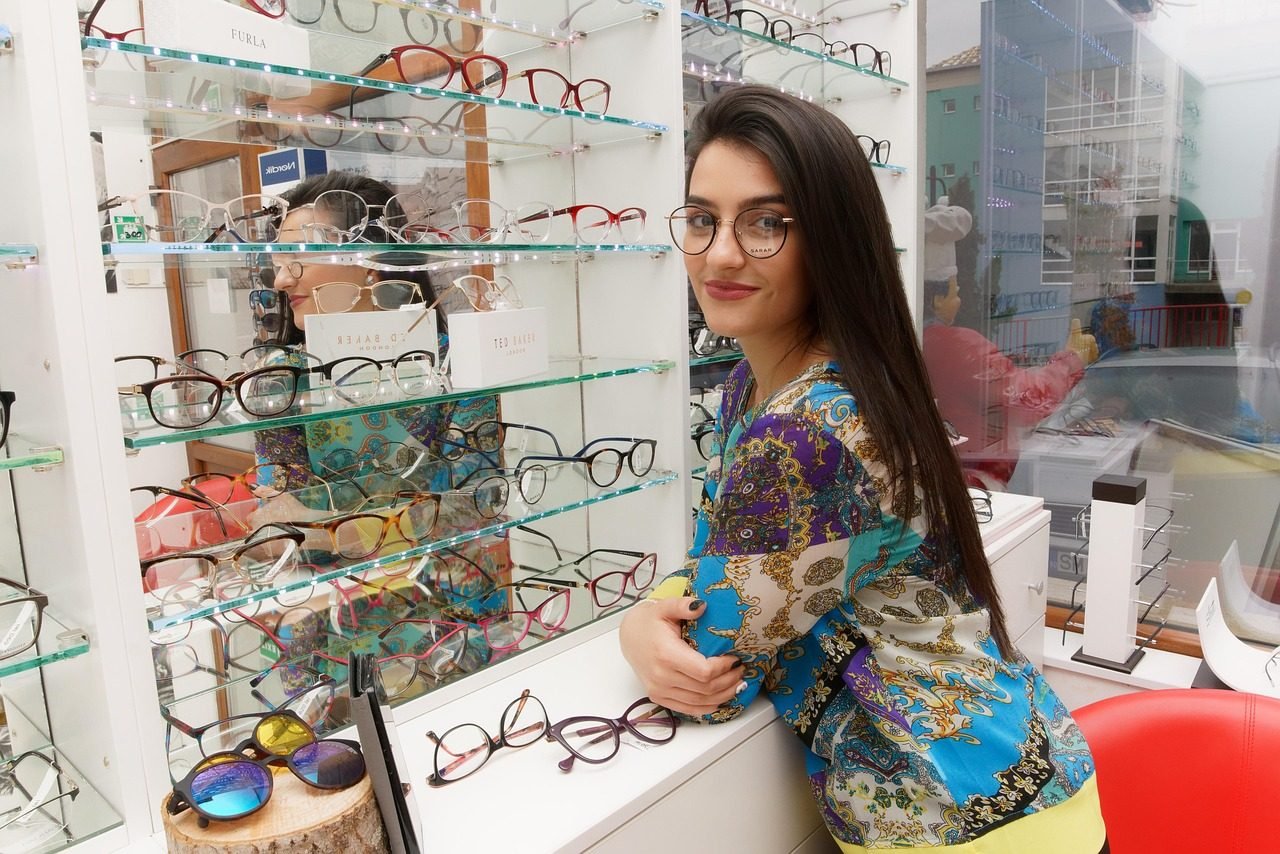 A customer looking along a wall of spectacle frames inside an optical store.